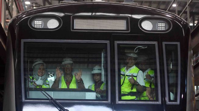 Gubernur DKI Jakarta Anies Baswedan (kedua kiri) bersama anaknya Kaisar Hakam (tengah), didampingi Direktur Utama PT MRT Jakarta William Sabandar (kedua kanan) dan masinis perempuan MRT Tiara (kiri) melambaikan tangan saat meninjau kepala kereta MRT di Depo MRT Lebak Bulus, Jakarta, Kamis (12/4). 