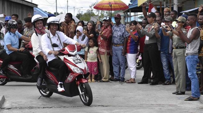 Presiden Joko Widodo berboncengan dengan Ibu Negara Iriana Joko Widodo menyapa warga saat kunjungan kerja di Distrik Agats, Kabupaten Asmat, Papua, Kamis (12/4). 