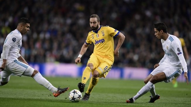 Striker Juventus Gonzalo Higuain melewati dua pemain Real Madrid [AFP]