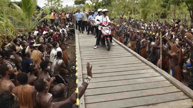 Presiden Joko Widodo berboncengan dengan Ibu Negara Iriana Joko Widodo menggunakan motor listrik menyapa warga Asmat saat kunjungan kerja di Kampung Kaye, Distrik Agats, Kabupaten Asmat, Papua, Kamis (12/4).