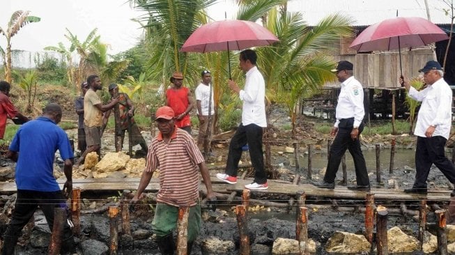 Presiden Joko Widodo (kiri) didampingi Menteri Pekerjaan Umum dan Perumahan Rakyat (PUPR) Basuki Hadimuljono (kanan) dan Gubernur Papua Barat Dominggus Mandacan (kedua kanan)mengunjungi pembangunan jalan program padat karya tunai di Kampung Kokoda, Distrik Sorong Manoi, Sorong, Papua Barat, Jumat (13/4).