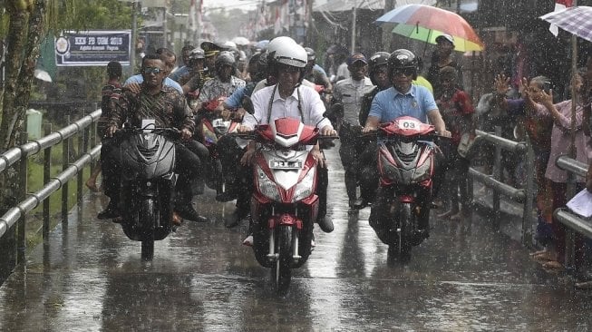 Presiden Joko Widodo membonceng istrinya, Iriana di atas skuter listrik ketika berkunjung ke Kampung Kaye, Distrik Agats, Kabupaten Asmat, Papua, Kamis (12/4). [Antara/Puspa Perwitasari]