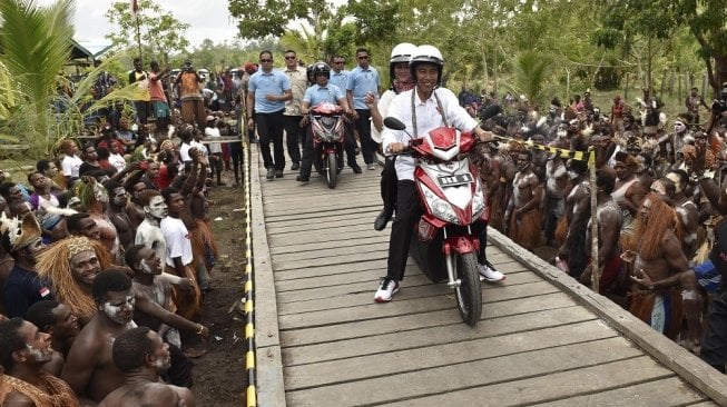 Presiden Joko Widodo membonceng istrinya, Iriana di atas skuter listrik ketika berkunjung ke Kampung Kaye, Distrik Agats, Kabupaten Asmat, Papua, Kamis (12/4). [Antara/Puspa Perwitasari]