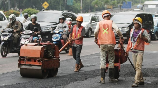 Petugas melakukan pengaspalan di sepanjang Jalan Gatot Subroto, Jakarta, Selasa (17/4).