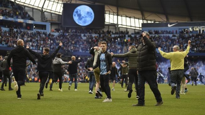 Fans Manchester City menyerbu lapangan Etihad Stadium usai tim kesayangan mereka berpesta gol ke gawang Swansea City, 5-0, Minggu (22/4/2018). [AFP/Oli Scarff]