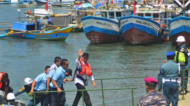 Presiden Joko Widodo (tengah) melambaikan tangan kepada warga seusai meninjau keramba ikan saat peresmian Keramba Jaring Apung atau "offshore" di Pelabuhan Pendaratan Ikan (PPI) Cikidang, Babakan, Kabupaten Pangandaran, Jawa Barat, Selasa (24/4).