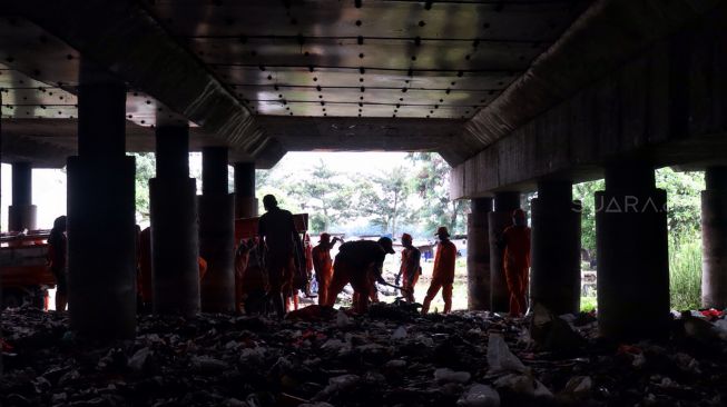 Petugas membersihkan sampah di kolong Jalan Tol Tanjung Priok, Jakarta, Selasa (24/4). 