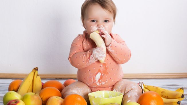 Illustration of a toddler eating fruit.  (Shutterstock)