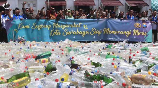 Petugas memusnakan puluhan minuman keras (Miras) oplosan dan ilegal di Polrestabes Surabaya, Jawa Timur, Rabu (25/4).