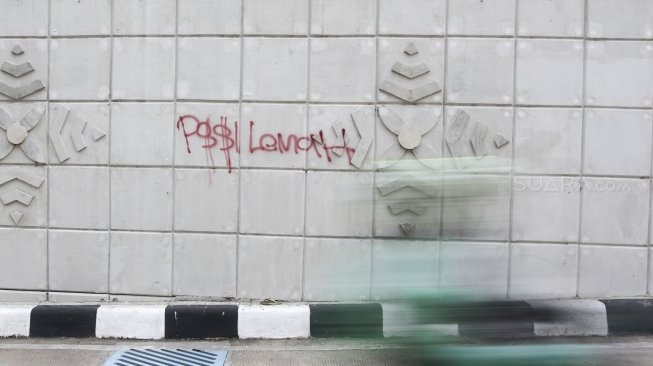 Pengendara melintas di samping coretan tangan jahil (Vandal di underpass Matraman, Jakarta, Rabu (2/5). 