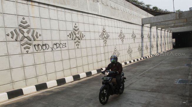 Pengendara melintas di samping coretan tangan jahil (Vandal di underpass Matraman, Jakarta, Rabu (2/5). 