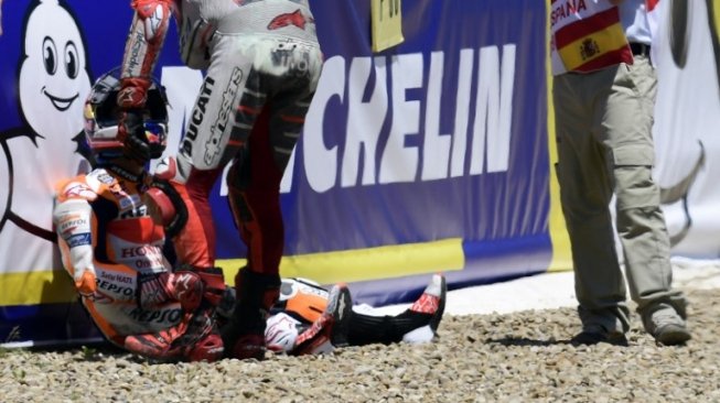 Pebalap Repsol Honda Dani Pedrosa duduk lemas di pinggir trek setelah mengalami kecelakaan di seri Spanyol [AFP]