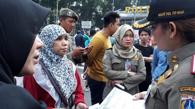 Petugas Satuan Polisi Pamong Praja DKI Jakarta menegur masyarakat yang menggunakan kaos bertuliskan #2019GantiPresiden di area Car Free Day, Bundaran Hotel Indonesia, Jakarta Pusat, Minggu (6/5/2018). (Suara.com/Dwi Bowo Raharjo)