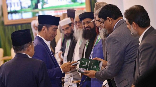 Presiden Joko Widodo (kedua kiri) didampingi Wakil Presiden Jusuf Kalla (kiri) menerima buku tentang Pakistan ketika menyalami sejumlah ulama yang mengikuti pertemuan trilateral ulama Afganistan, Indonesia dan Pakistan di Istana Bogor, Jawa Barat, Jumat (11/5).