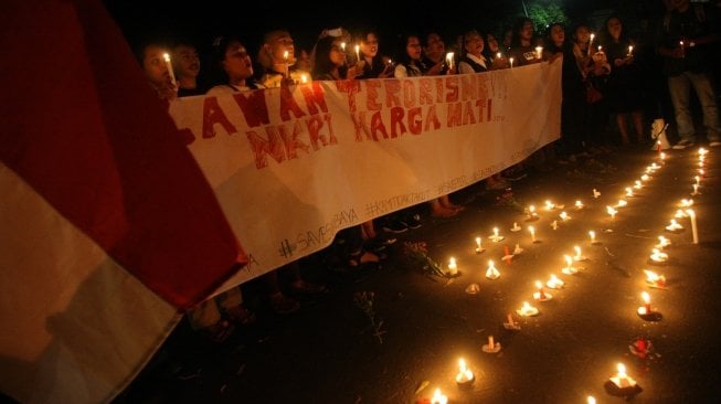 Warga membawa spanduk saat aksi solidaritas lawan terorisme di halaman TMP Radin Wijaya, Blitar, Jawa Timur, Minggu (13/5) malam. Aksi yang digelar berbagai elemen mahasiswa, tokoh agama, serta masyarakat pengguna jalan tersebut untuk mendoakan para korban ledakan bom di Surabaya serta mendeklarasikan diri untuk melawan aksi terorisme. ANTARA