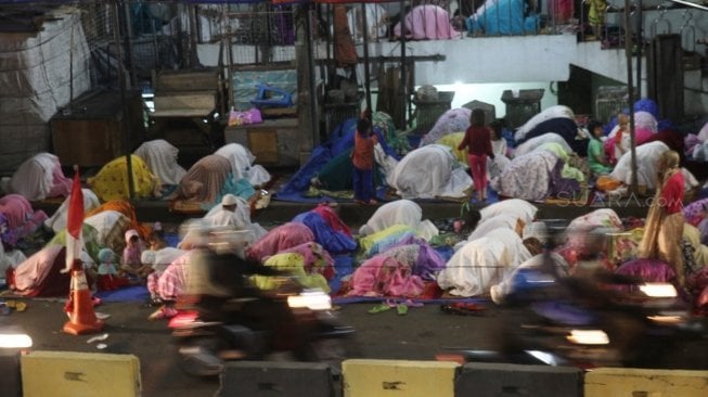 Warga melaksanakan salat Tarawih pertama Ramadan 1439 H di sisi jalan dan jembatan penyeberangan di kawasan Pasar Gembrong, Jatinegara, Jakarta Timur, Rabu (16/5/2018) malam. [Suara.com/Oke Atmaja]