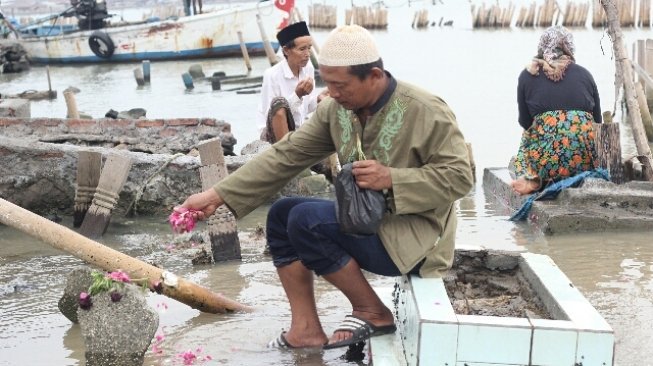 Warga berziarah di makam kerabatnya di tempat pemakaman umum (TPU) yang terdampak abrasi di Tambaklorok, Semarang, Jawa Tengah, Rabu (16/5/2018). [Suara.com/Adam Iyasa]