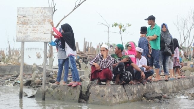 Warga berziarah di makam kerabatnya di tempat pemakaman umum (TPU) yang terdampak abrasi di Tambaklorok, Semarang, Jawa Tengah, Rabu (16/5/2018). [Suara.com/Adam Iyasa]