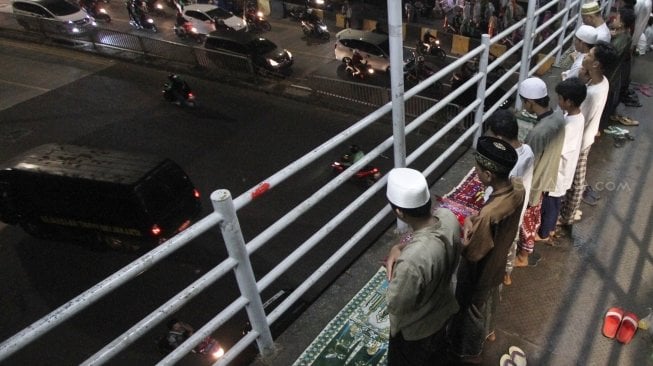 Warga melaksanakan salat Tarawih pertama Ramadan 1439 H di sisi jalan dan jembatan penyeberangan di kawasan Pasar Gembrong, Jatinegara, Jakarta Timur, Rabu (16/5/2018) malam. [Suara.com/Oke Atmaja]