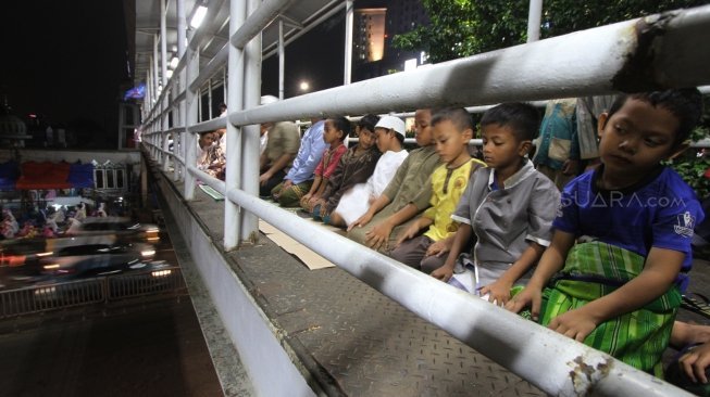 Warga melaksanakan salat Tarawih pertama Ramadan 1439 H di sisi jalan dan jembatan penyeberangan di kawasan Pasar Gembrong, Jatinegara, Jakarta Timur, Rabu (16/5/2018) malam. [Suara.com/Oke Atmaja]