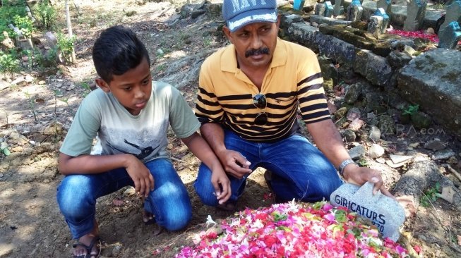 Marvel sang anak di makam Giri Catur S, korban aksi teror bom mobil Arjuno, di Tempat Pemakaman Umum (TPU) Gunungsari, Surabaya, Sabtu (19/5/2018). [Suara.com/Achmad Ali]