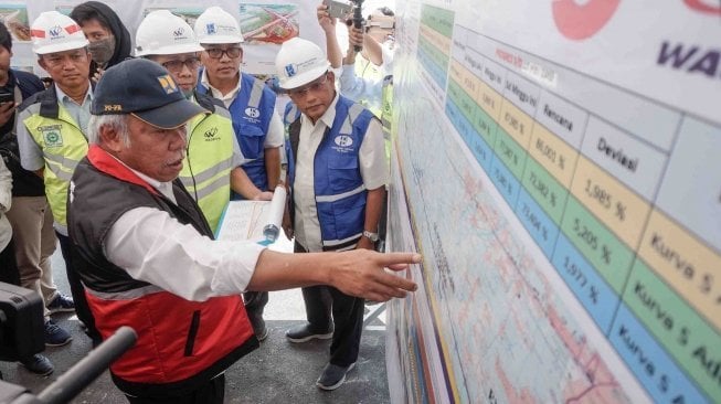 Menteri Pekerjaan Umum dan Perumahan Rakyat (PUPR) Basuki Hadimuljono (kiri) mengamati papan perkembangan pembangunan tol di Pemalang, Jawa Tengah, Sabtu (26/5). 