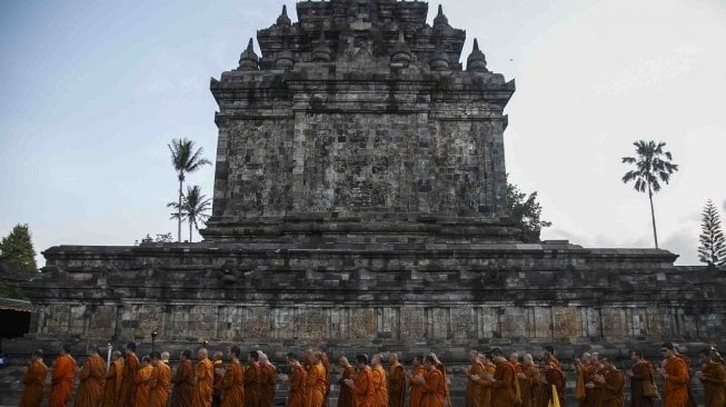 Sejumlah Bhiksu melakukan pradaksina atau mengelilingi candi membawa Api Dharma dengan obor yang diambil dari api abadi Mrapen Kabupaten Grobogan saat prosesi penyemayaman Api Dharma Waisak 2018 di Candi Mendut, Magelang, Jawa Tengah, Minggu (27/5). 