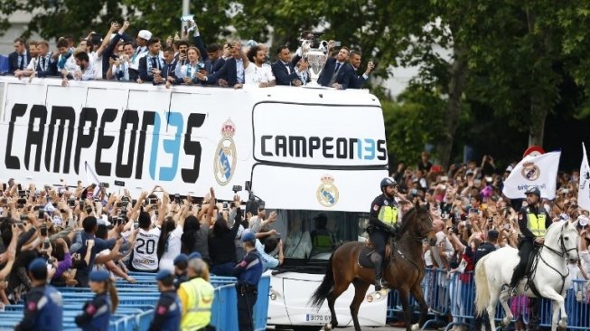 Para pemain Real Madrid melakukan parade juara Liga Champions dengan bus atas terbuka di jalan-jalan ibukota Spanyol. BENJAMIN CREMEL / AFP
