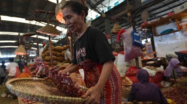 Seorang pekerja memilah bawang merah yang dijual di Pasar Induk Kramat Jati, Jakarta, Selasa (29/5). 