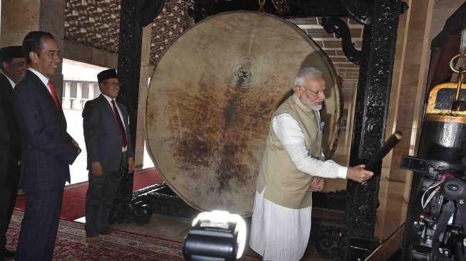 PM India Narendra Modi (kanan) mencoba memukul bedug disaksikan Presiden Joko Widodo (kiri) ketika mengunjungi Masjid Istiqlal, Jakarta, Rabu (30/5). 