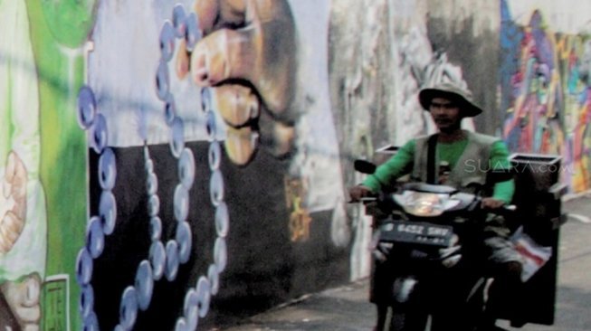 Warga melintas di samping mural di kawasan Jagakarsa, Jakarta, Jumat (1/6).