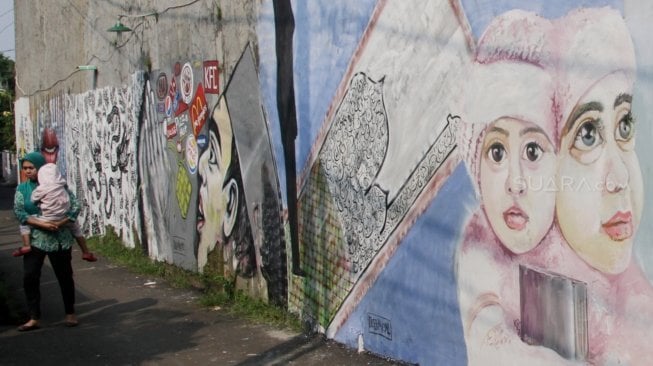 Warga melintas di samping mural di kawasan Jagakarsa, Jakarta, Jumat (1/6).