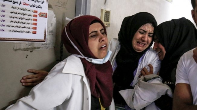 Rekan-rekan almarhumah Razan Al Najjar sesama tim medis berduka atas kepergian teman mereka tersebut, di lorong Rumah Sakit Khan Younis di sebelah selatan Jalur Gaza, Palestina, Jumat (1/6/2018). [Said Khatib/AFP]