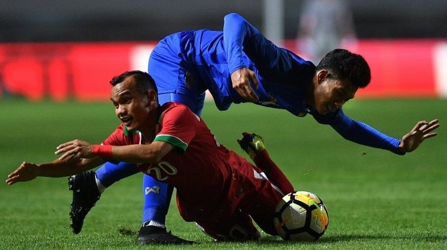 Pemain Timnas Indonesia U-23 Riko Simanjuntak (kiri) dijatuhkan pemain Timnas Thailand U-23 Chaiyawat Buran dalam pertandingan uji coba di Stadion Pakansari, Cibinong, Bogor, Jawa Barat, Minggu (3/6) malam. ANTARA