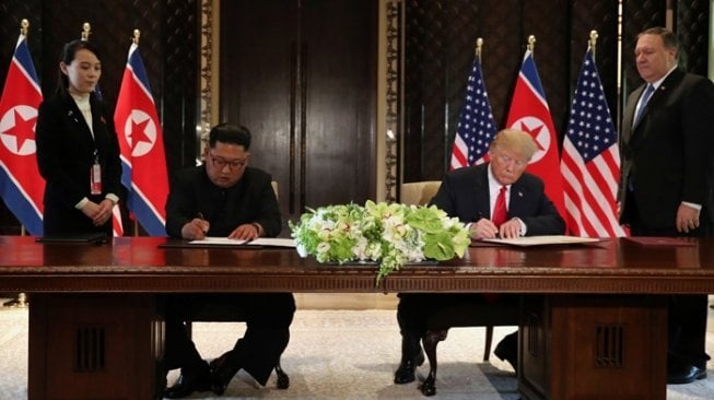 Pemimpin Korea Utara Kim Jong Un dan Presiden Amerika Serikat Donald Trump menandatangani dokumen sebagai puncak pertemuan bersejarah mereka di Pulau Sentosa, Singapura, Selasa (12/6/2018). [Reuters/Jonathan Ernst]