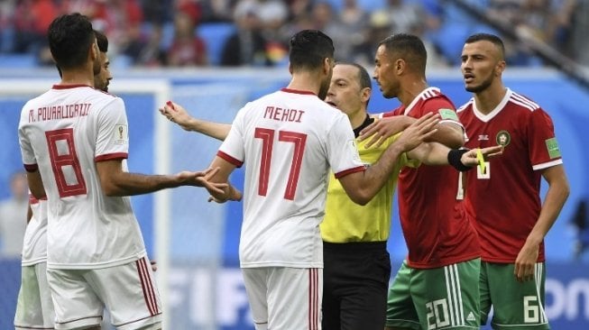 Wasit Cuneyt Cakir menenangkan pemain Maroko dan Iran yang bertikai di pertandingan Grup B Piala Dunia 2018, Jum'at (15/6/2018) [AFP]