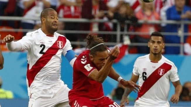 Pemain depan Denmark Yussuf Poulsen (tengah) berebut bola dengan bek Peru Alberto Rodriguez (kiri). Jack GUEZ / AFP