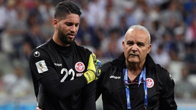 Kiper Timnas Tunisia Mouez Hassen (kiri) yang mengalami cedera bahu di laga kontra Inggris, terlihat bersedih saat harus meninggalkan lapangan untuk digantikan kiper pengganti Farouk Ben Mustapha (Mark RALSTON / AFP)