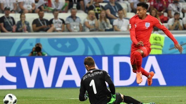 Gelandang serang Timnas Inggris, Jesse Lingard (kanan) mencoba menaklukkan kiper pengganti Tunisia, Farouk Ben Mustapha (Mark RALSTON / AFP)