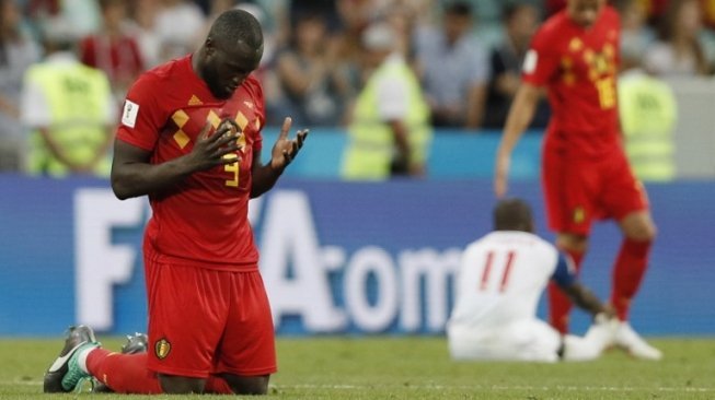 Striker Belgia, Romelu Lukaku berlutut di akhir laga melawan Panama di Piala Dunia 2018, Senin (18/6). [AFP/Adrian Dennis]
