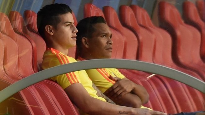 Gelandang Kolombia James Rodriguez (kiri) dan striker Kolombia, Carlos Bacca duduk menyaksikan sesi latihan, Senin (18/6), jelang laga antara Kolombia vs Jepang di Piala Dunia 2018 keesokan harinya. [AFP/Juan Berreto]