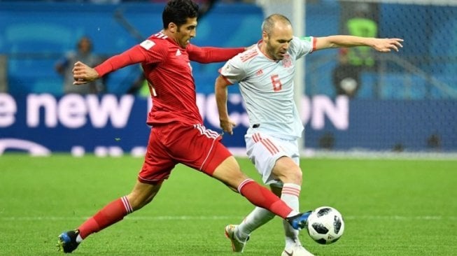 Gelandang Timnas Spanyol, Andres Iniesta (kanan), mencoba melewati hadangan penyerang Iran, Vahid Amiri, dalam laga penyisihan Grup B Piala Dunia 2018 yang berakhir 1-0 untuk kemenangan Spanyol, Rabu (20/6/2018). [AFP/Saeed Khan]