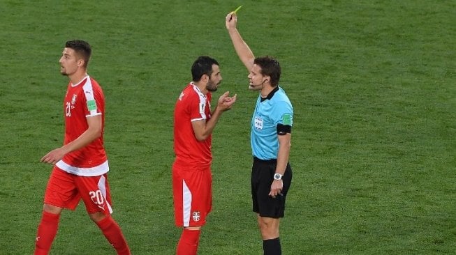 Gelandang Timnas Serbia Luka Milivojevic (tengah) diganjar kartu kuning oleh wasit Felix Brych (kanan) pada laga kontra Swiss (Patrick HERTZOG / AFP)