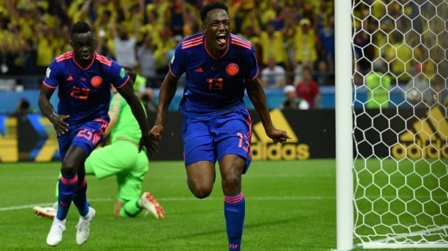 Bek Kolombia Yerry Mina (kanan) merayakan golnya ke gawang Polandia. SAEED KHAN / AFP