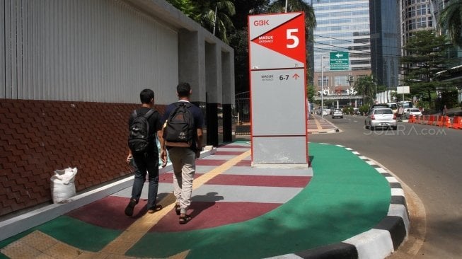 Warga melintas di pintu masuk kompleks Gelora Bung Karno (GBK), Jakarta, Selasa (26/6).