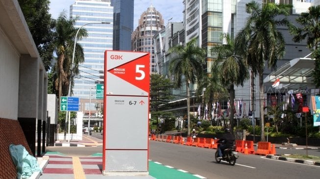 Warga melintas di pintu masuk kompleks Gelora Bung Karno (GBK), Jakarta, Selasa (26/6).