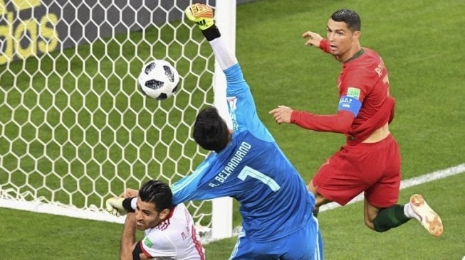 Penyerang Timnas Portugal Cristiano Ronaldo (kanan) dan kiper Iran Alireza Beiranvand sama-sama coba meraih bola di laga matchday pamugkas Grup B Piala Dunia 2018 di Mordovia Arena (Mladen ANTONOV / AFP)