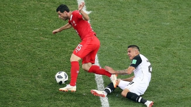 Gelandang Timnas Swiss, Blerim Dzemaili (kiri), mendapat tekel dari pemain Kosta Rika, dalam laga Grup E Piala Dunia 2018 yang berakhir imbang 2-2 di Nizhny Novgorod Stadium, Rusia, Kamis (28/6) dini hari WIB. [Foto: Anadolu]