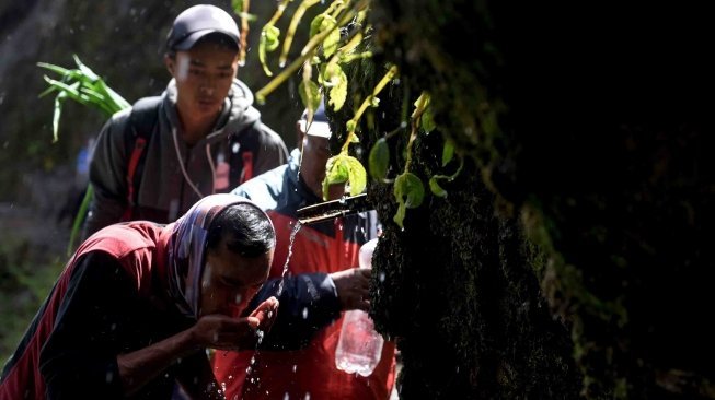 Masyarakat Suku Tengger meminum air dari mata air Gunung Widodaren saat ritual pengambilan air suci di kawasan Gunung Bromo, Probolinggo, Jawa Timur, Jumat (29/6). 