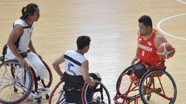 Pebasket kursi roda Indonesia Kasep Ayatollah (kanan) mencoba melewati pebasket Thailand Tawatchai Jiasin (kiri) dan Chaichana Kaewkaleong pada ajang Indonesia Para Games Invitational Tournament di Kompleks Gelora Bung Karno, Senayan, Jakarta, Senin (2/7).